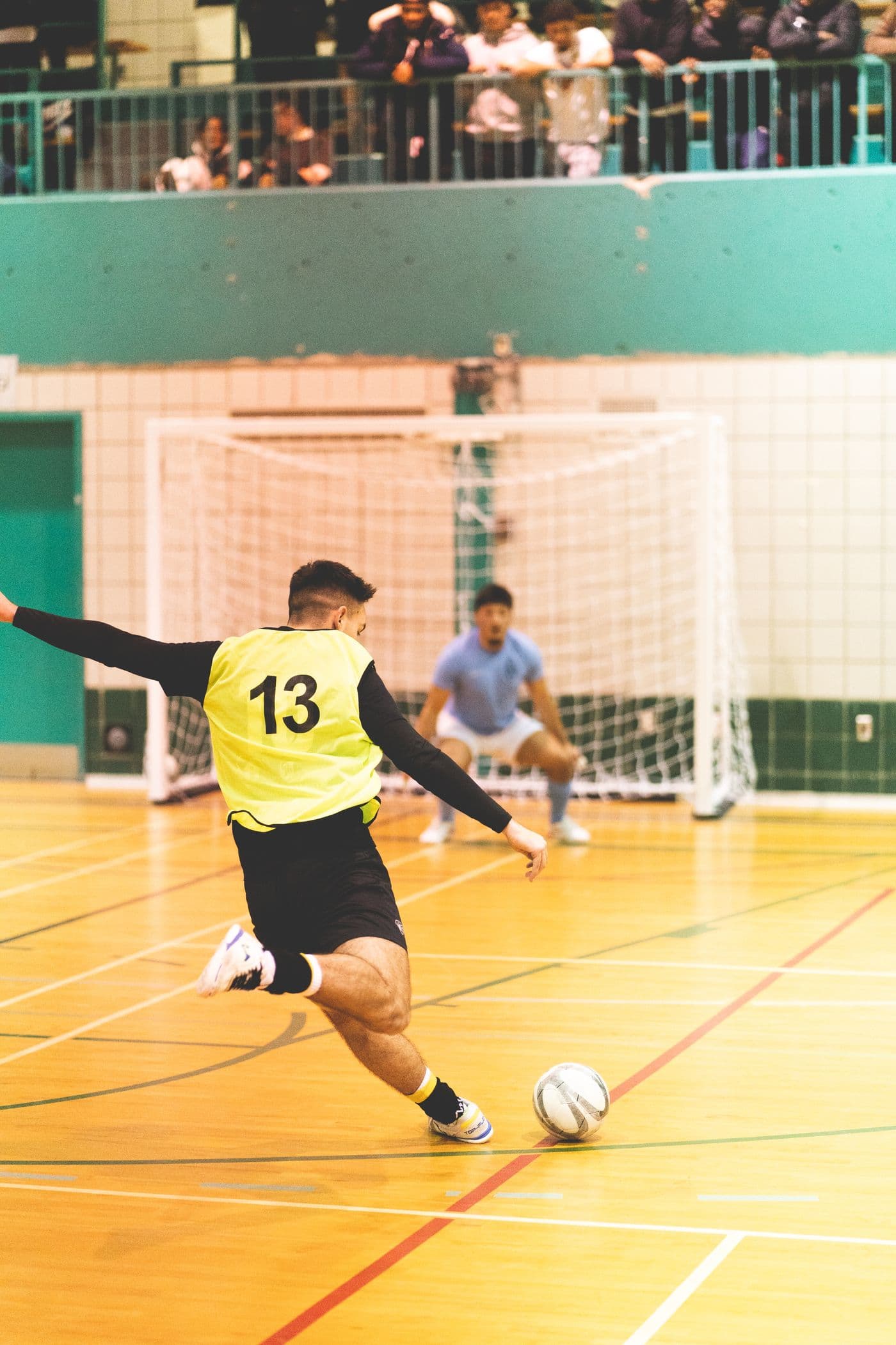 Jugador de futsal rematando al arco en una cancha techada