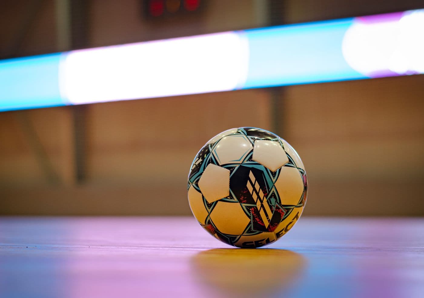 Pelota de futsal sobre el parquet con las luces del gimnasio de fondo